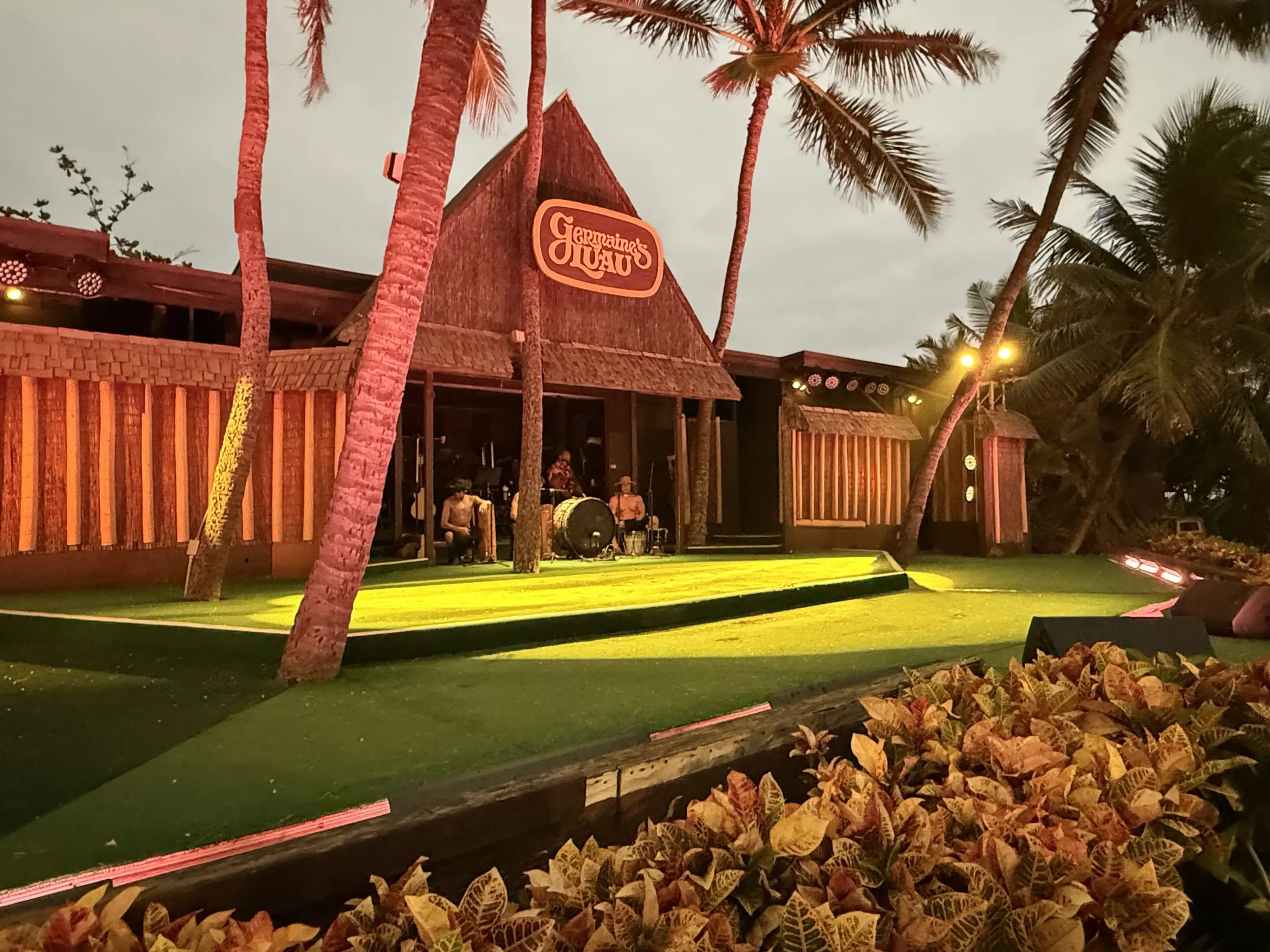 Tropical-themed mini golf course illuminated at dusk with palm trees.