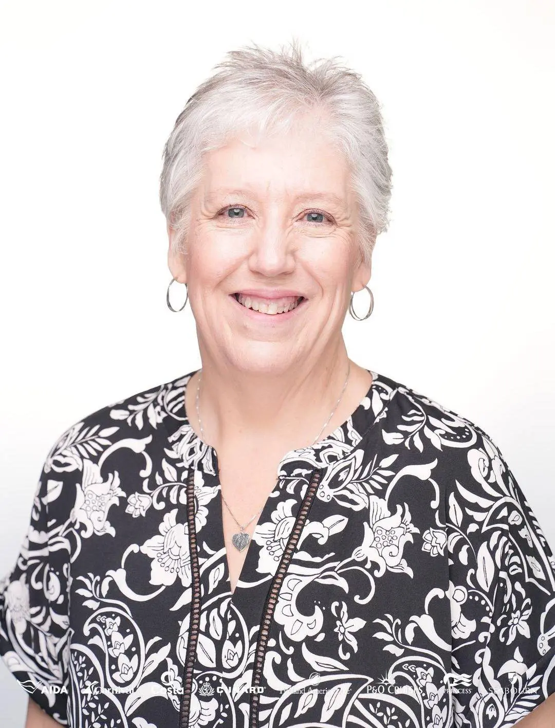 Smiling older woman with short white hair in a patterned blouse.