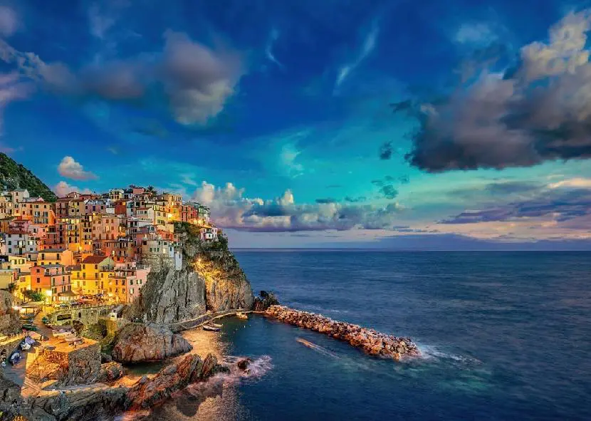Colorful cliffside village overlooking a calm sea at sunset.